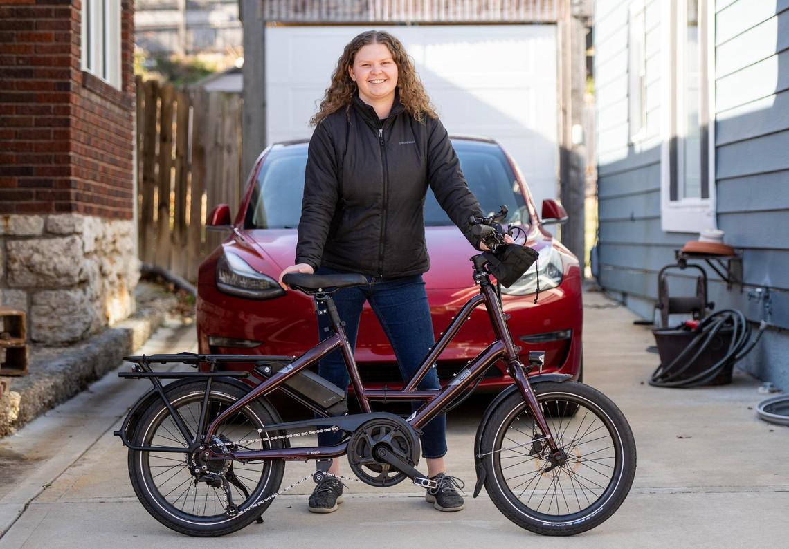 Gayle Bergman, an environmental scientist, poses for a photo with her electric bicycle and car outside her home on Tuesday, Nov. 22, 2022 in Kansas City, Kan.