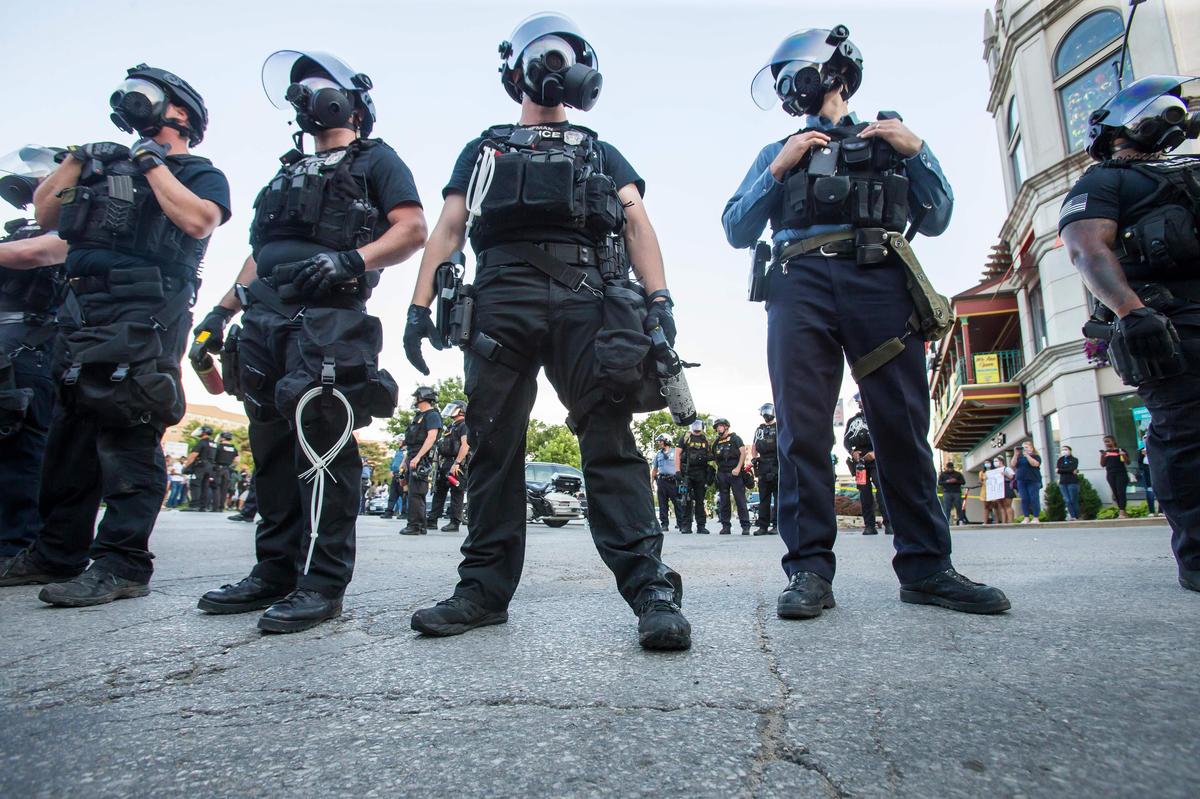 Kansas City police officers stand at the ready Saturday at the Country Club Plaza during a protest to bring awareness to the death of George Floyd who died in the custody of Minneapolis police. The protest turned violent later in the night when stores on the Plaza were vandalized and at least one police car was set on fire. Police used tear gas in an attempt to control the crowd.
