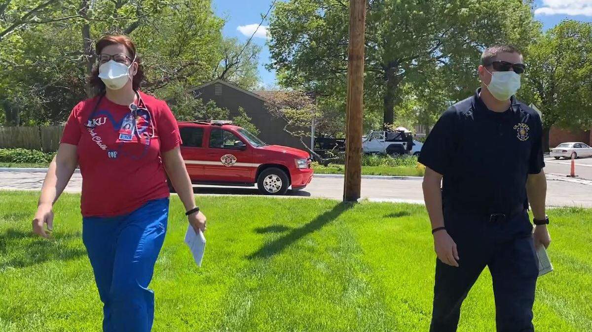 Central Elementary School nurse Sarah Gilliland and firefighter Chris Curtis stop by the home of an Olathe School District family to check and see if they need any help.
