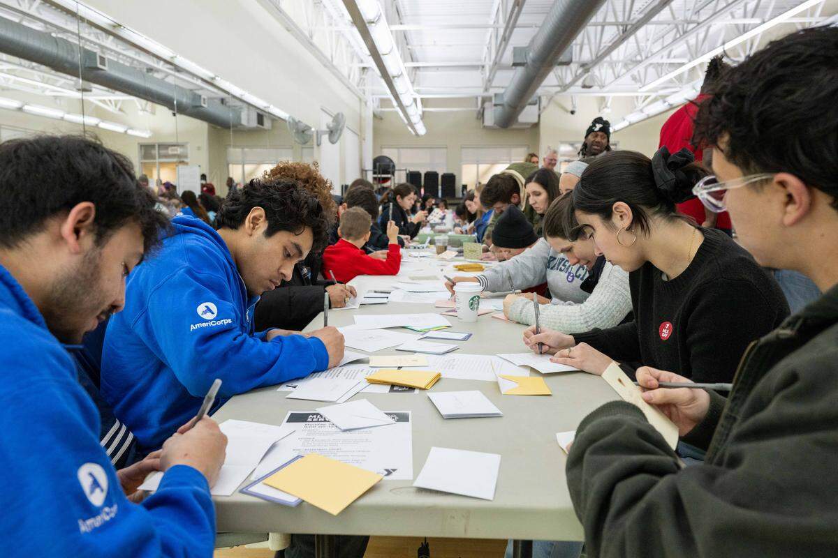 Young people write handwritten notes of encouragement at Cleaver Family YMCA in Kansas City on Monday, January 19, 2026 to celebrate Martin Luther King Jr. Day. Volunteers wrote notes to young people, veterans, and people that deal with food scarcity. The notes would be included in a care package that includes food, sanitary items, and a bed mat made of plastic bags.