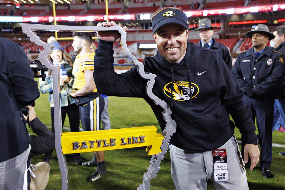 Coach Eli Drinkwitz of the Missouri Tigers poses with the Battle Line Trophy after the game against the Arkansas Razorbacks at Donald W. Reynolds Razorback Stadium on November 24, 2023, in Fayetteville.
