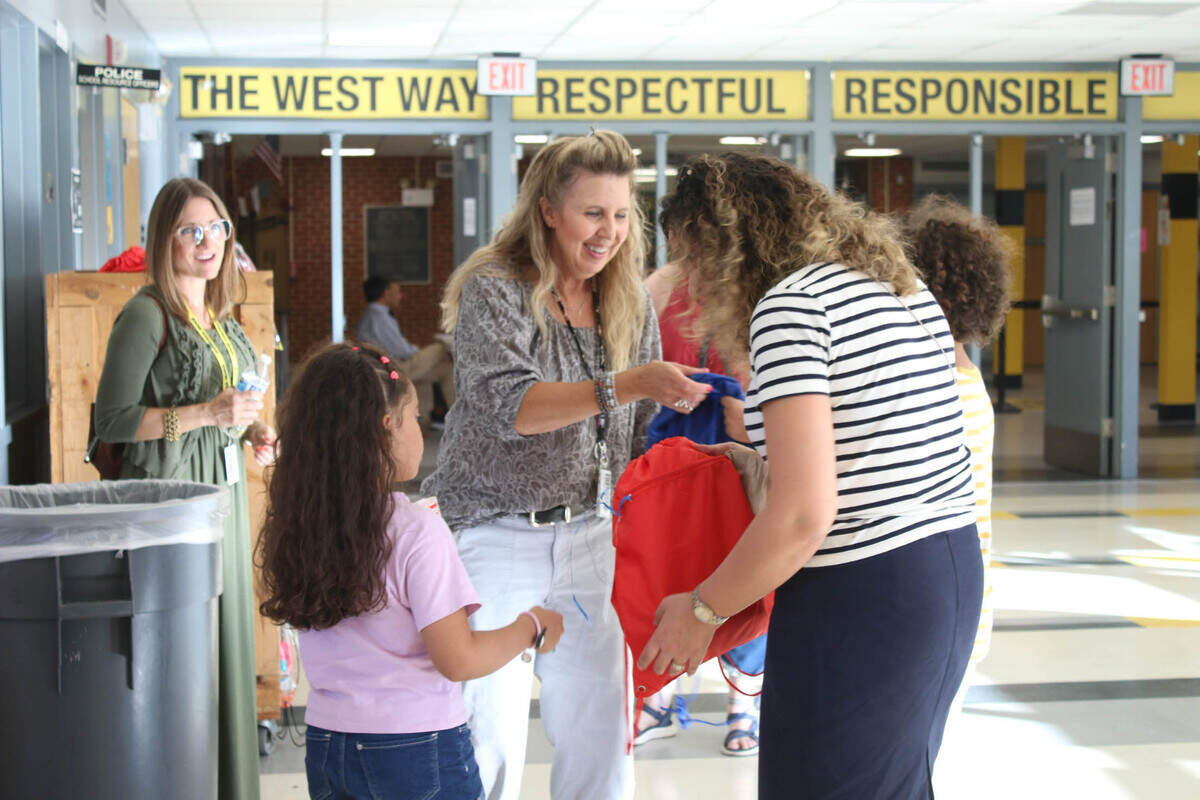 Karen Crosby, an ELL teacher at Shawnee Mission West, gives Anais Bouguerra and her mom, Hanane Chikhi, free school supplies at the district’s multilingual community event.