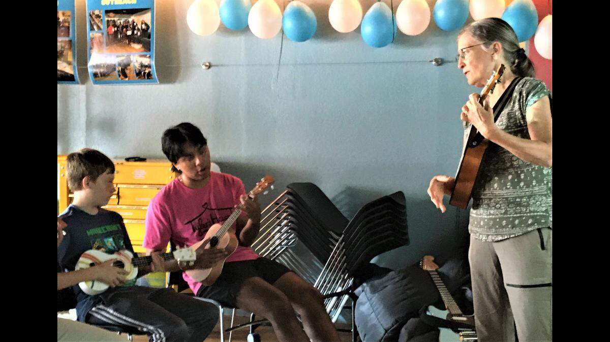 Caden Churchill, left, and Yahir Fernandez learn ukulele chords from Susan Kaldahl, a volunteer at Tyler’s House KC in Mission. Tyler’s House provides teens with free entertainment, food and a safe place to hang out.