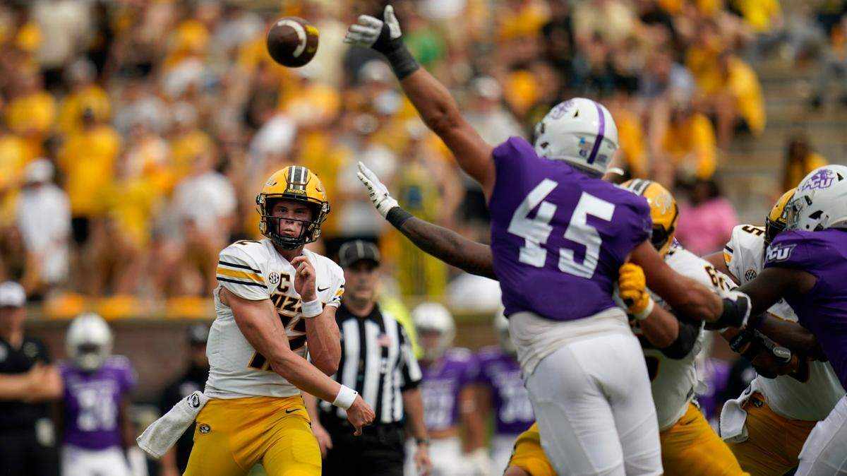 Missouri quarterback Brady Cook, left, throws a 13-yard touchdown pass as Abilene Christian defensive lineman Jordan Paup leaps in vain on Saturday in Columbia.