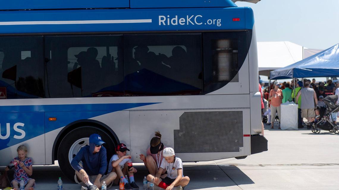 People eat in the shade cast by a RideKC bus during the Garmin KC Air Show on Saturday, Aug. 19, 2023, in New Century.