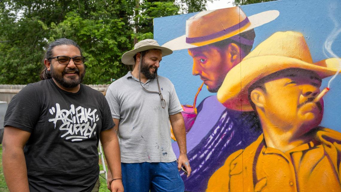 Muralists Rodrigo “Rico” Alvarez, right, and Isaac Tapia take a break from working on a scaled down version of a mural in Tapia’s backyard. The artists take photos of their practice designs and then reference the work from their smartphones while they paint the final version.