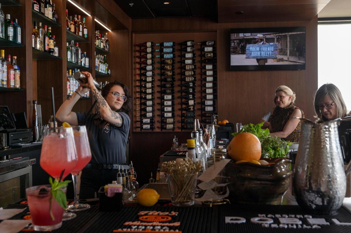 Bartender Jessica Deister prepares cocktails for customers in the open bar area at Roots Seasonal Cuisine.