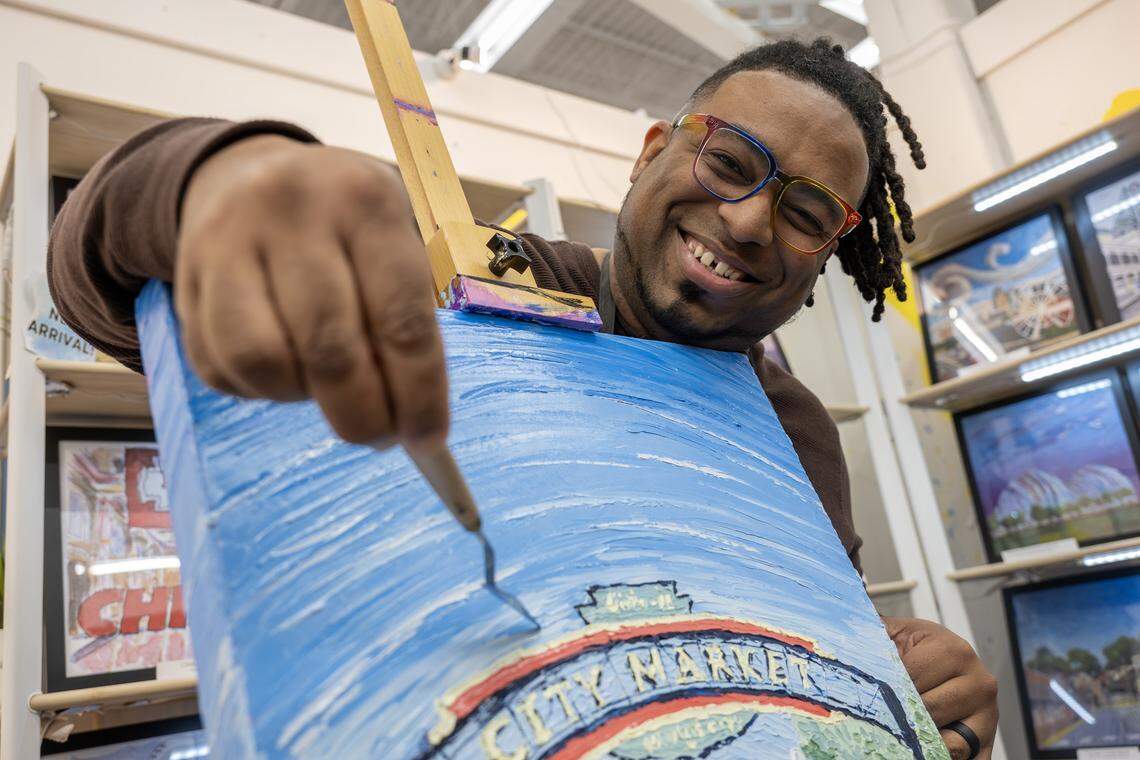 Artist Theo Davis smiles for a portrait alongside an original oil painting at his booth inside Painted Tree on Tuesday, Dec. 16, 2025, in Kansas City.