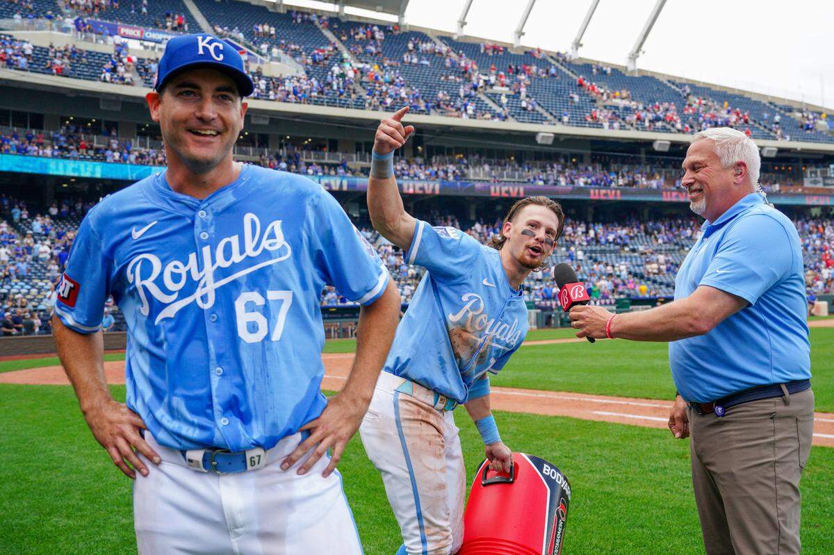 Kansas City Royals shortstop Bobby Witt Jr. (7) speaks to Bally Sports announcer Joel Goldberg, leading fans in a “Let’s go Lugo” chant, as starting pitcher Seth Lugo (67) looks on after the win over the Chicago White Sox at Kauffman Stadium on July 21, 2024.