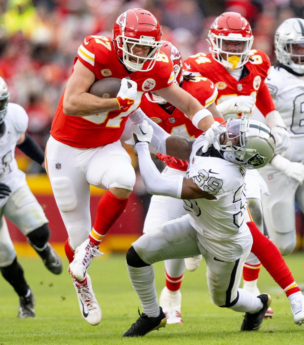 Kansas City Chiefs tight end Travis Kelce (87) stiff arms Las Vegas Raiders cornerback Nate Hobbs (39) during an NFL football game on Monday, Dec. 25, 2023, at Arrowhead Stadium at GEHA Field in Kansas City.