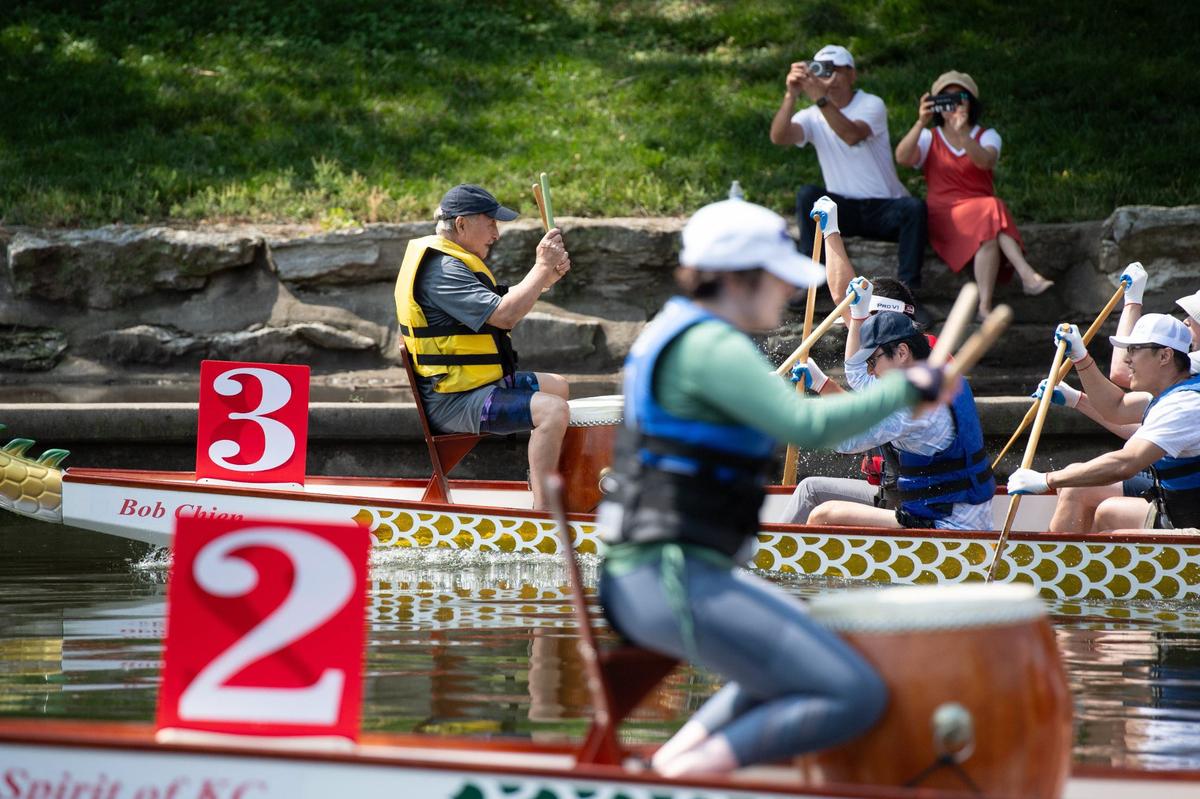 Spectators photograph two neck-and-neck teams during a dragon boat race at the 18th annual Kansas City Dragon Boat Festival.