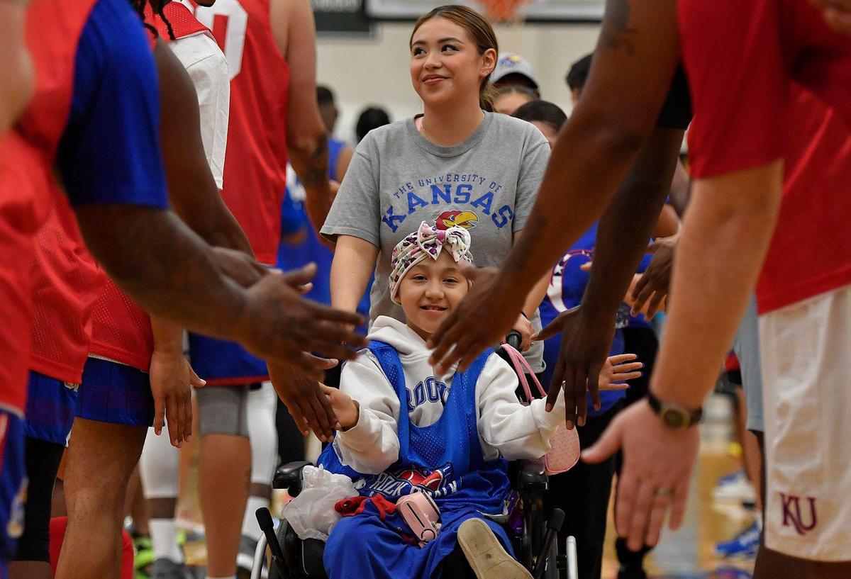 Fatima Gomez, 9, of Olathe, is introduced and is greeted by former KU basketball players during Thursday night’s Rock Chalk Roundball Classic at Free State High School in Lawrence. The annual game pits crimson and blue teams made up of former KU basketball players in a charity game to raise money for families fighting cancer. Gomez is battling Osteosarcoma and fought her way through a partial leg amputation.