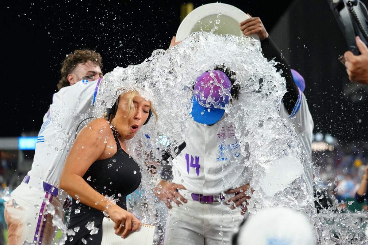 KANSAS CITY, MISSOURI - JUNE 19: Tricia Whitaker sideline reporter for Apple TV and Jac Caglianone #14 of the Kansas City Royals are doused with water after a game against the St. Louis Cardinals at Kauffman Stadium on June 19, 2026 in Kansas City, Missouri. (Photo by Ed Zurga/Getty Images)