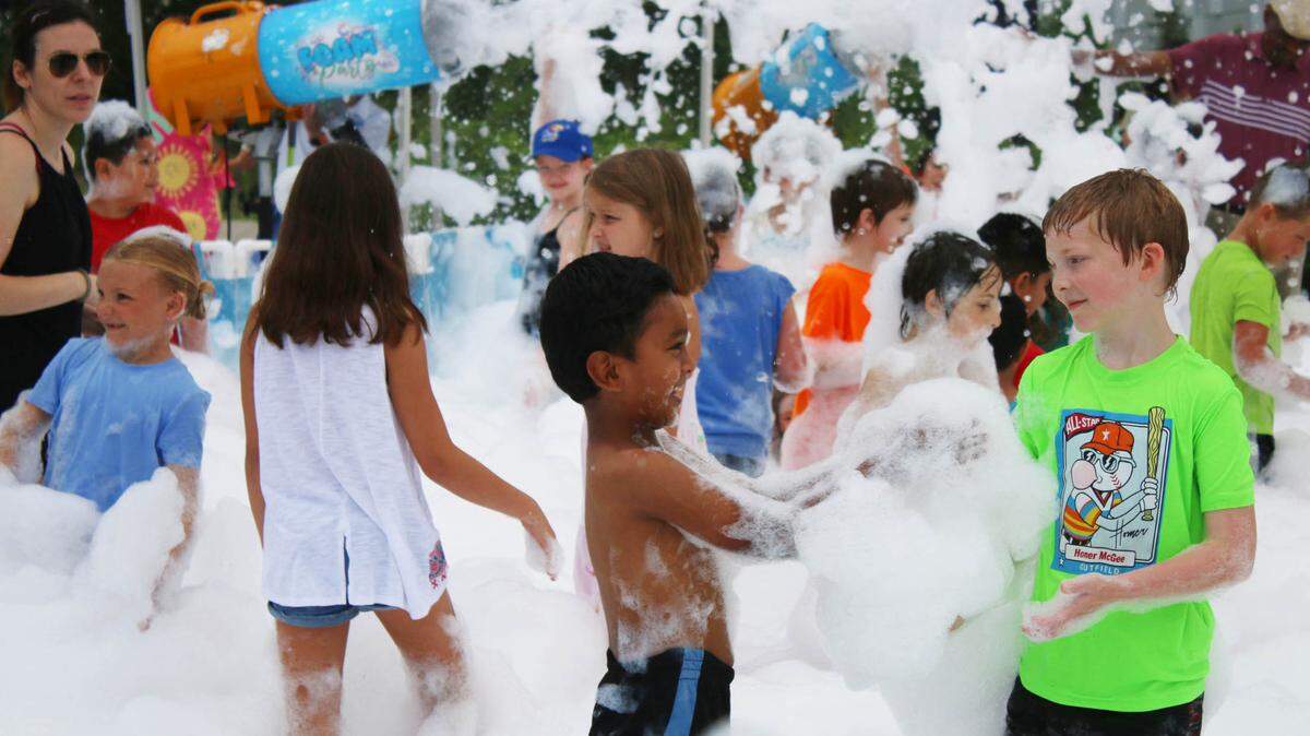 Children play in a mass of bubbles during the foam party at Indian Creek Library in Olathe.