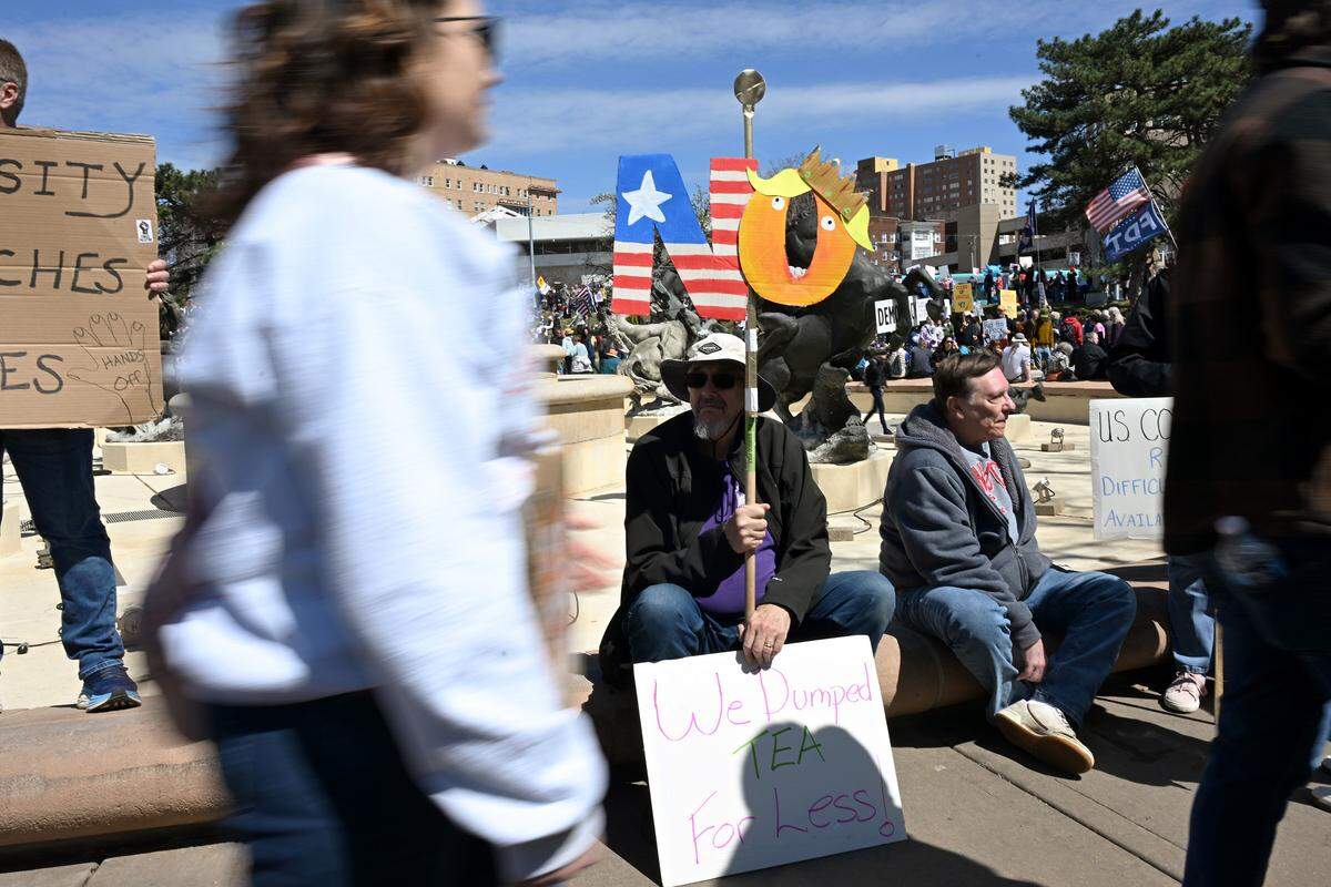 Protesters sit by the Mill Creek Fountain during a No Kings protest at Mill Creek Park near the Country Club Plaza on Saturday, March 28, 2026, in Kansas City.