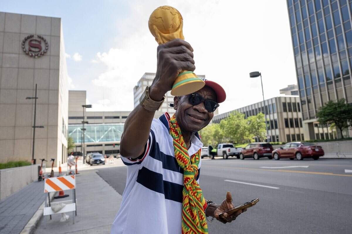 A Ghana fan waves a replica FIFA World Cup trophy in the air while waiting outside the Sheraton Kansas City Hotel for the Ghana national team to arrive on Wednesday, July 1, 2026.