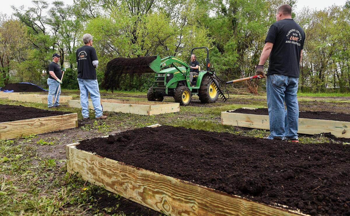 Phil Meyer, a garden manager with Kansas City Community Gardens, fills a new raised bed with a topsoil and compost mix as volunteers wait to level it. A small army of volunteers helped give Freeway Park Community Garden in Kansas City’s historic Northeast a makeover for its 20th anniversary. The garden, near E. 14th Street and Indiana Avenue, is managed by Kansas City Community Gardens, which rents plots to neighborhood gardeners.