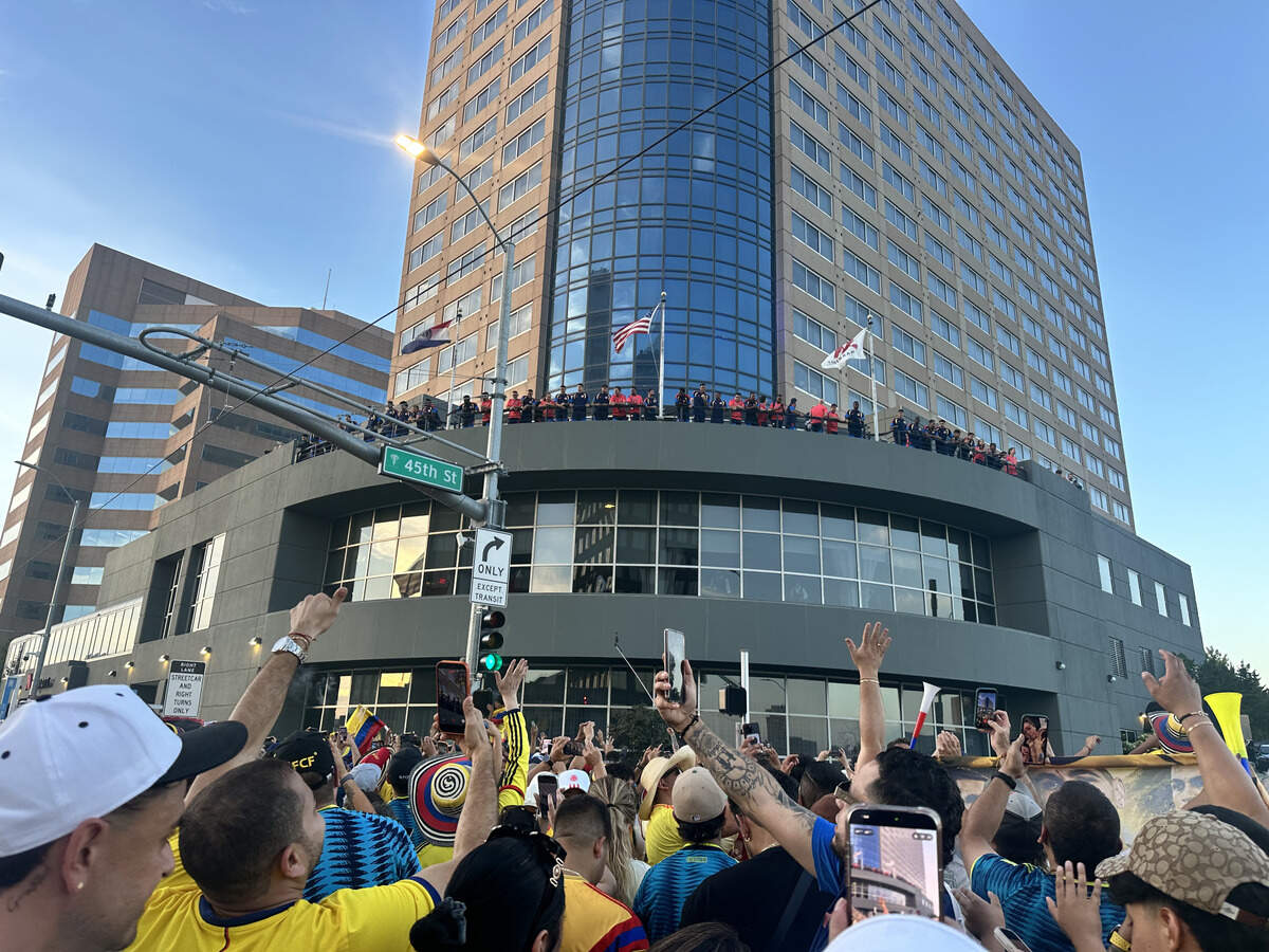 Fans raise their hands up to the Colombian national team as the athletes watch from the balcony of the Marriott Hotel on Main Street.