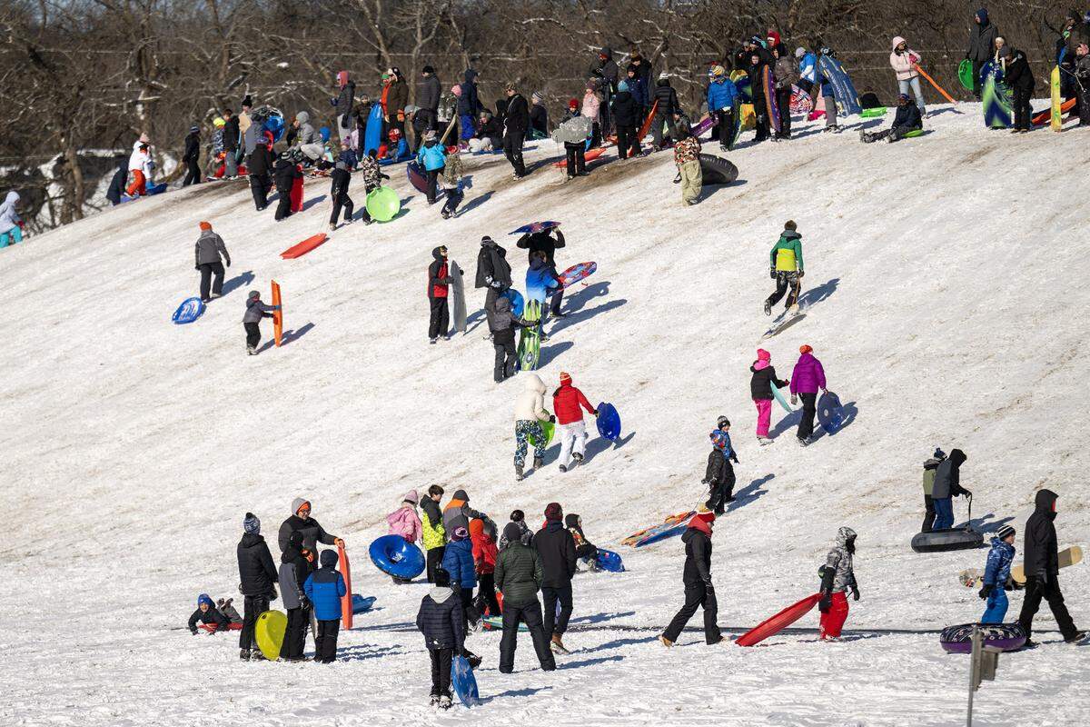 Sledders hit a traffic jam on the slope at Meadowbrook Park on Sunday, Jan. 25, 2026 in Prairie Village. The frigid temperatures were no match for the crowd gathered to enjoy the aftermath of the weekend's winter storm.