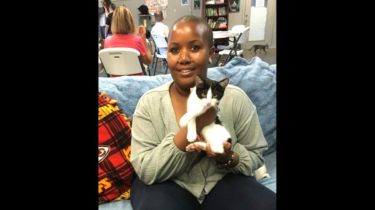 Stella Kibathi of Overland Park snuggles with a kitty at Second Cup Cat Cafe in Olathe.