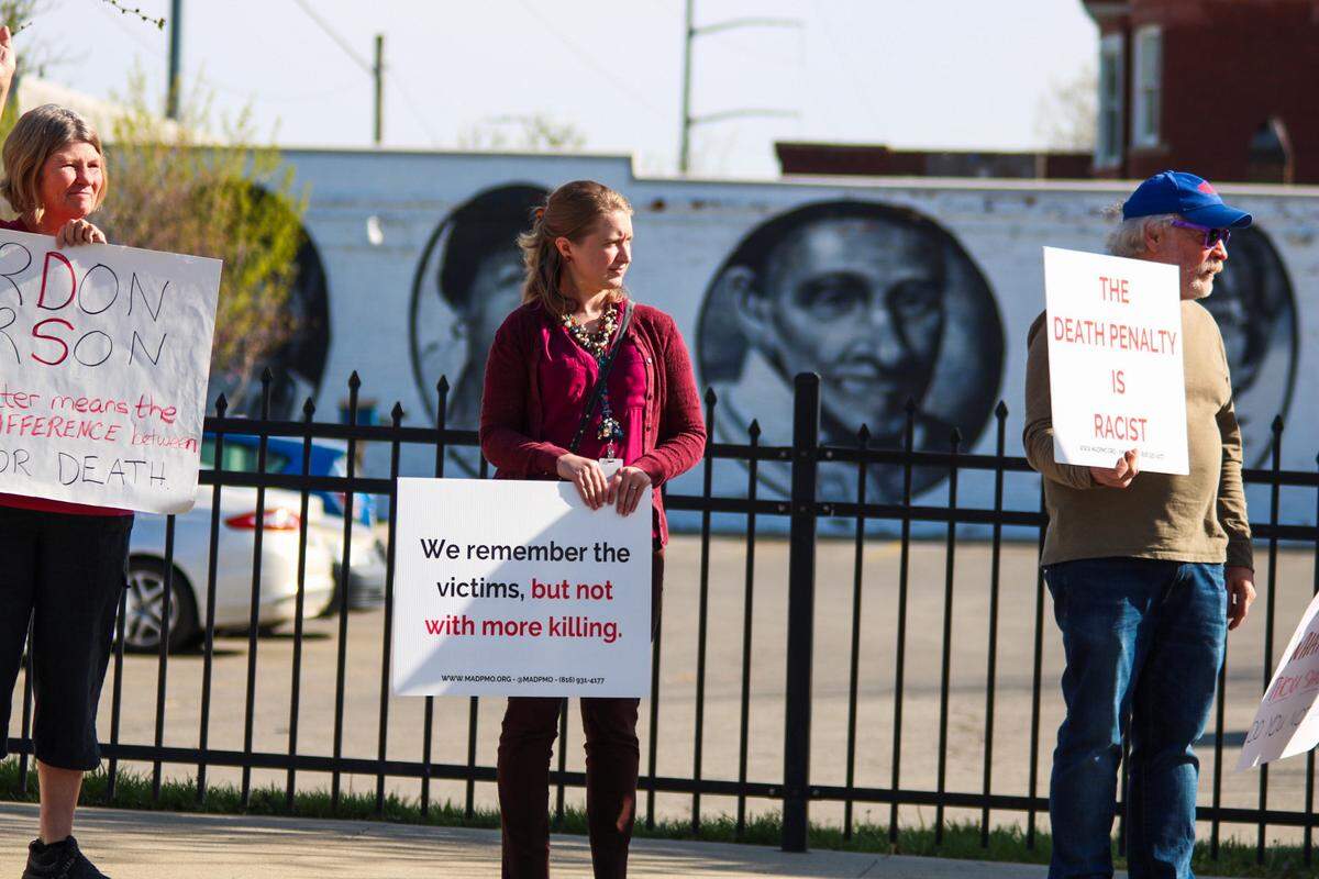 Chelsea Voboril (middle) stands with protesters Tuesday near 39th Street and Troost Avenue as they call for Missouri to abolish the death penalty.