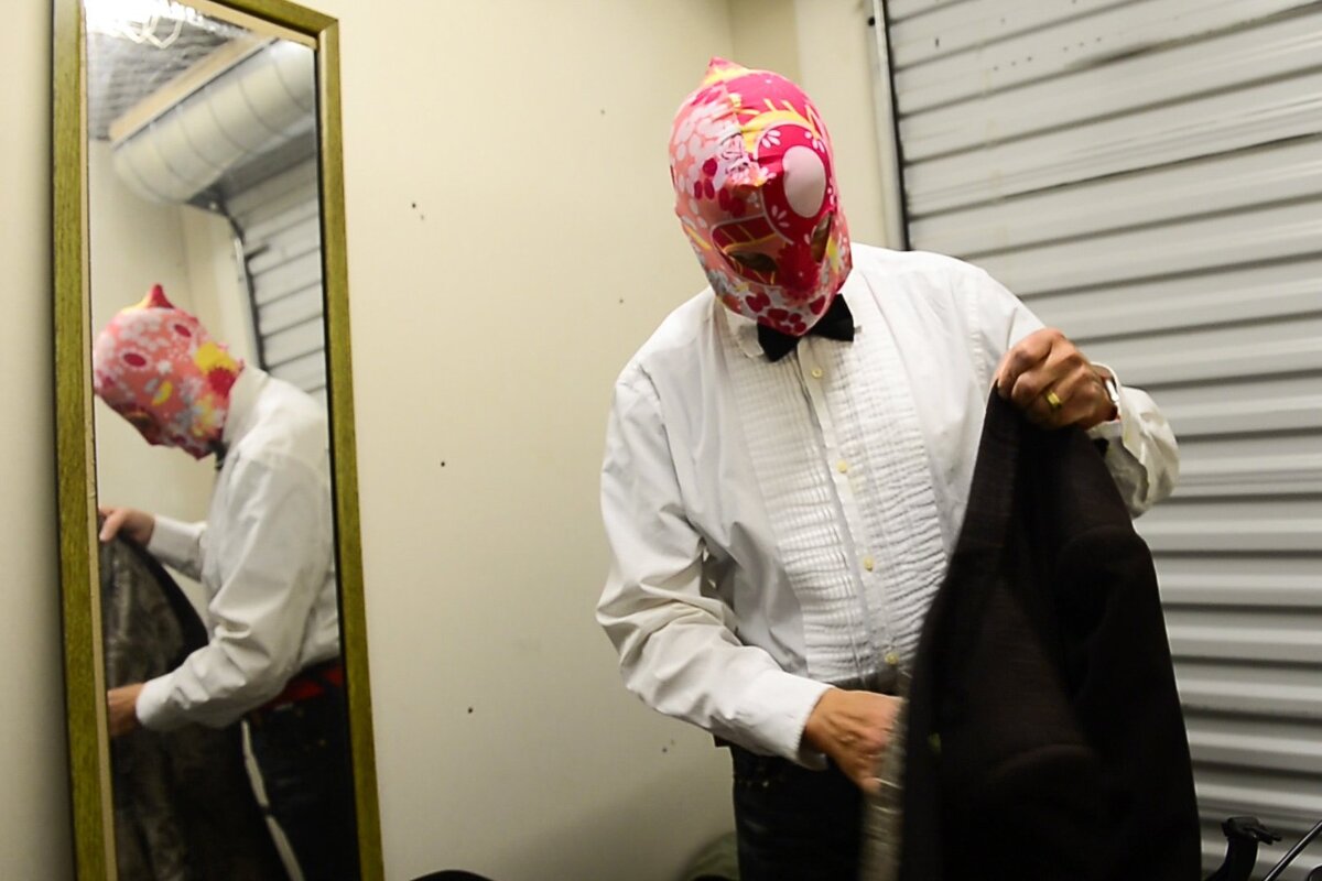 Dr. MooMoo puts on his pink floral mask and dark brown coat in his apartment storage unit before he hit the streets.