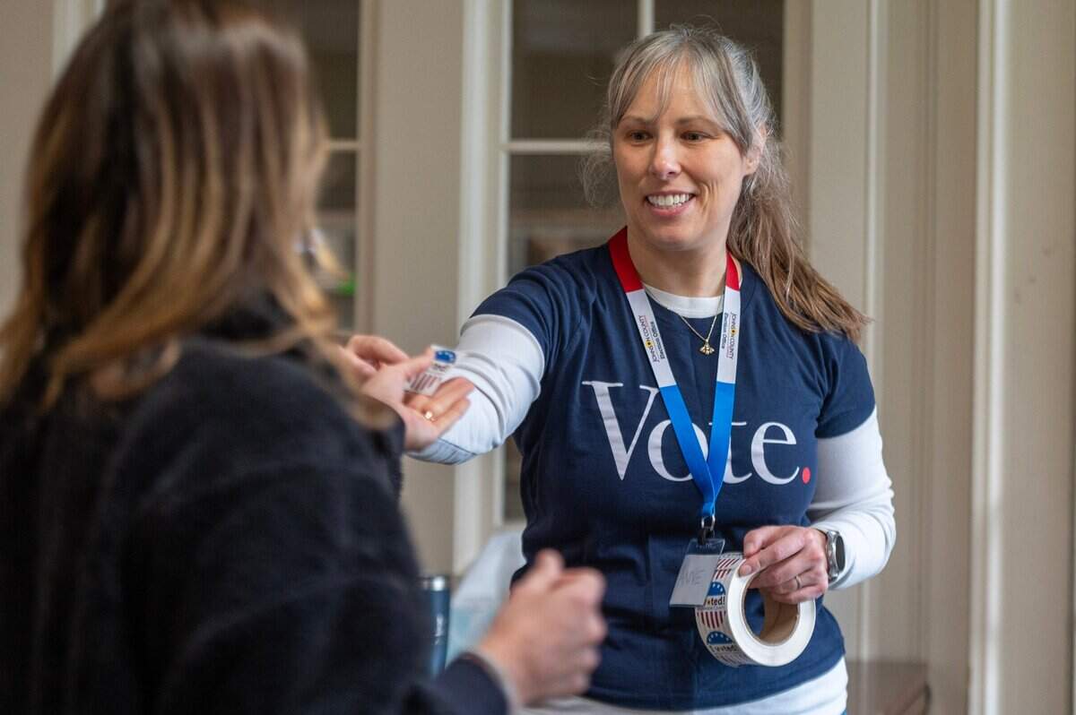 Anne Jones, a polling volunteer, hands out stickers after voters cast their ballots at Asbury United Methodist Church in Prairie Village on Tuesday, Nov. 7.