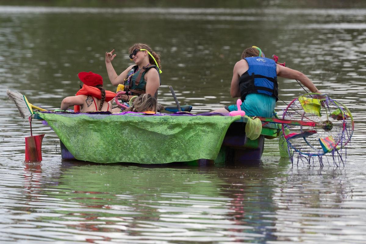 Toby South steers his homemade hot tub boat as Rheg gestures to another boater Saturday during the Kawsmouth River Carnival.