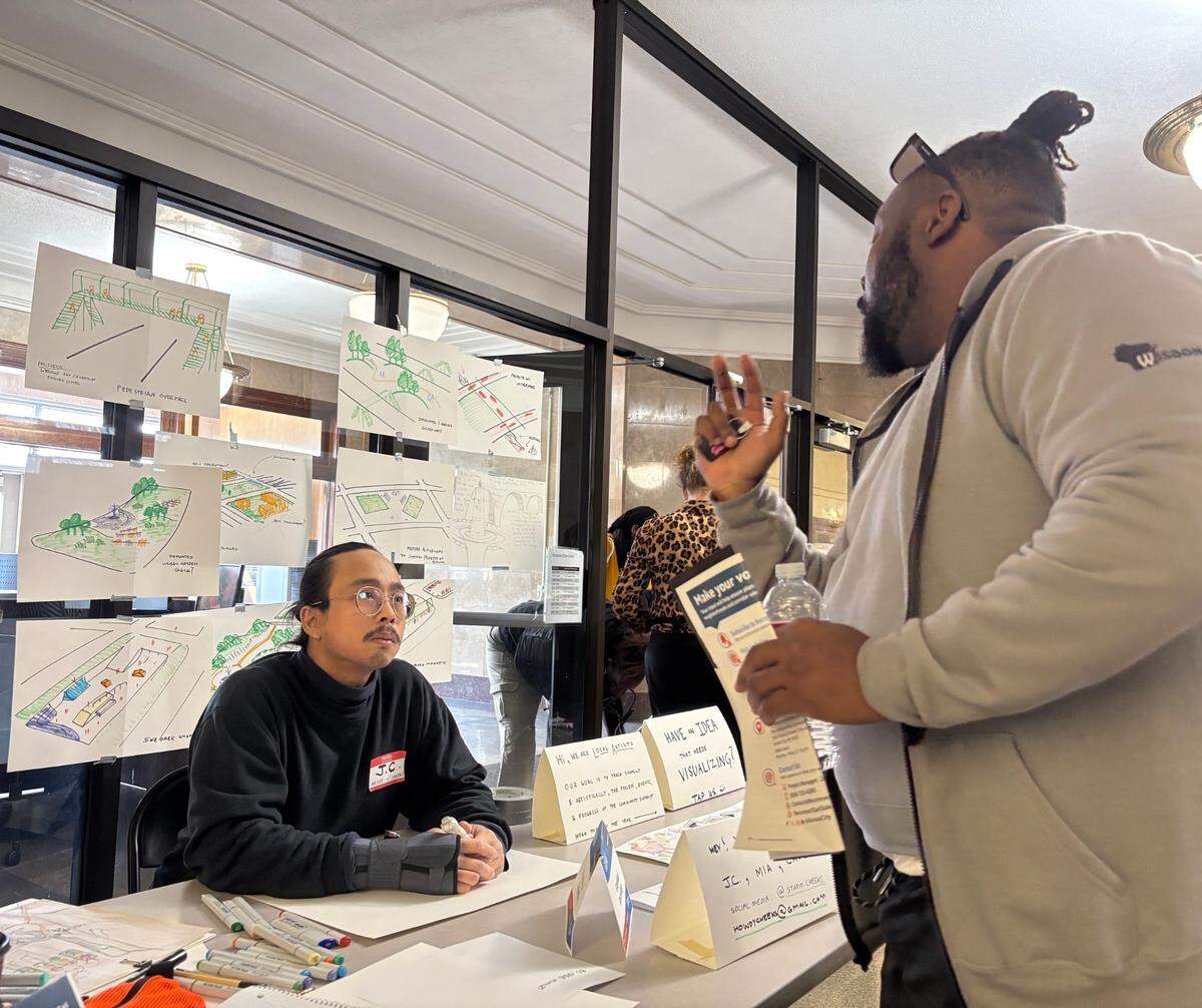 Jay Jones with MORE2 shares his ideas for 71 Highway with J.C. Franco, artist with Studio Cheeks. The two attended the Reconnecting the East Side event at Southeast High School on March 22.