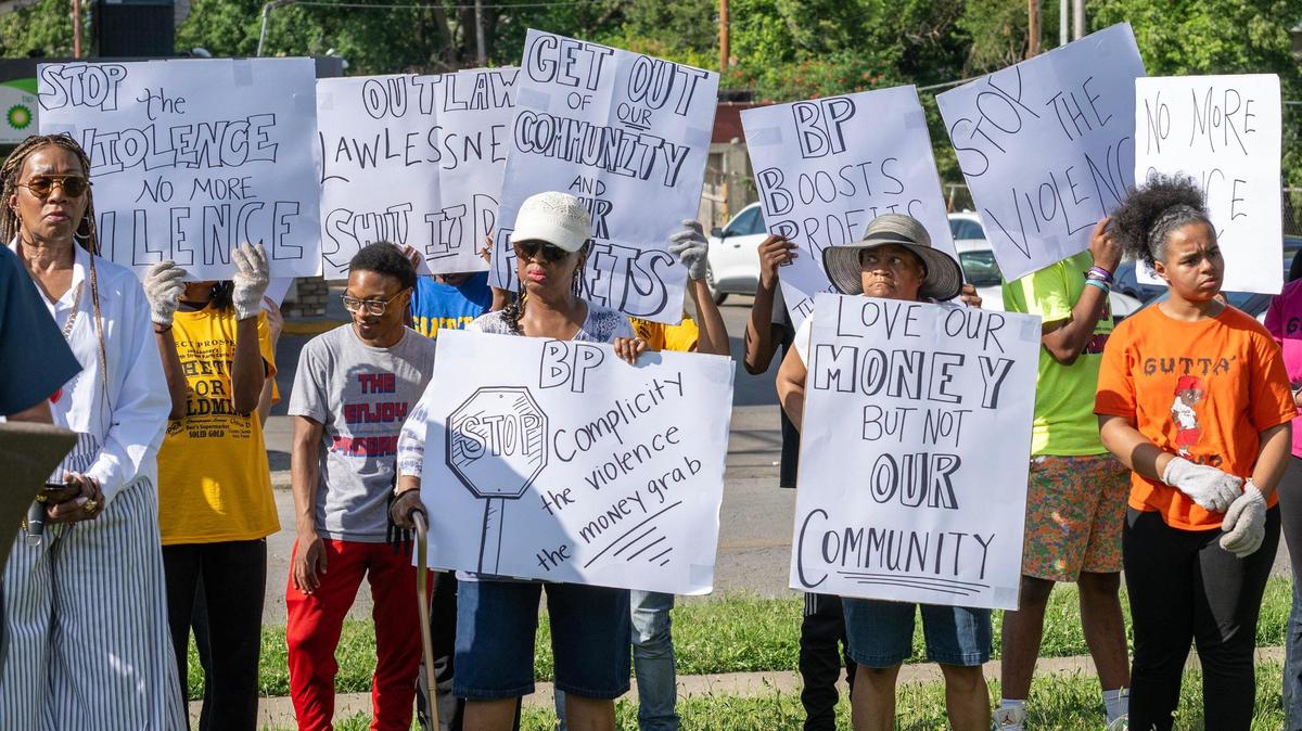 Community members hold signs during a press conference at the corner of Prospect Avenue and 35th Street on Monday, June 23, 2025, in Kansas City. The event focused on recent violence in the area and efforts to promote business accountability.