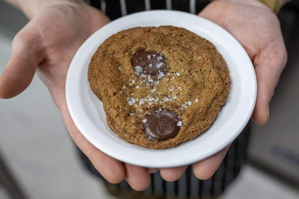 Pastry chef Nichole Taylor holds out one of her chocolate chip cookies on a small plate at Sister Anne's Coffee and Records Thursday, Dec. 4, 2025, in Kansas City.