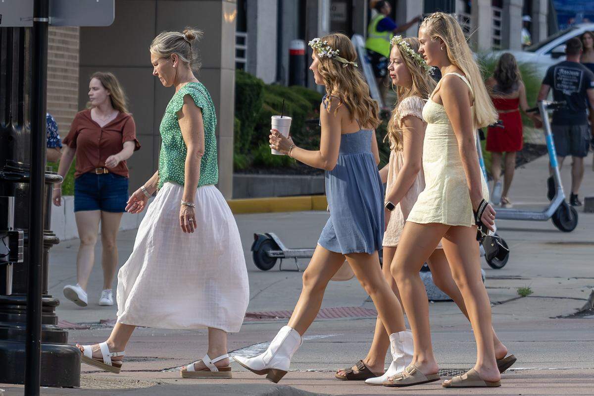 Fans wearing flower crowns, boots, and floral dresses walk across the street near the T-Mobile Center before The Lumineers' Automatic World Tour performance on Saturday, July 26, 2025, in Kansas City.