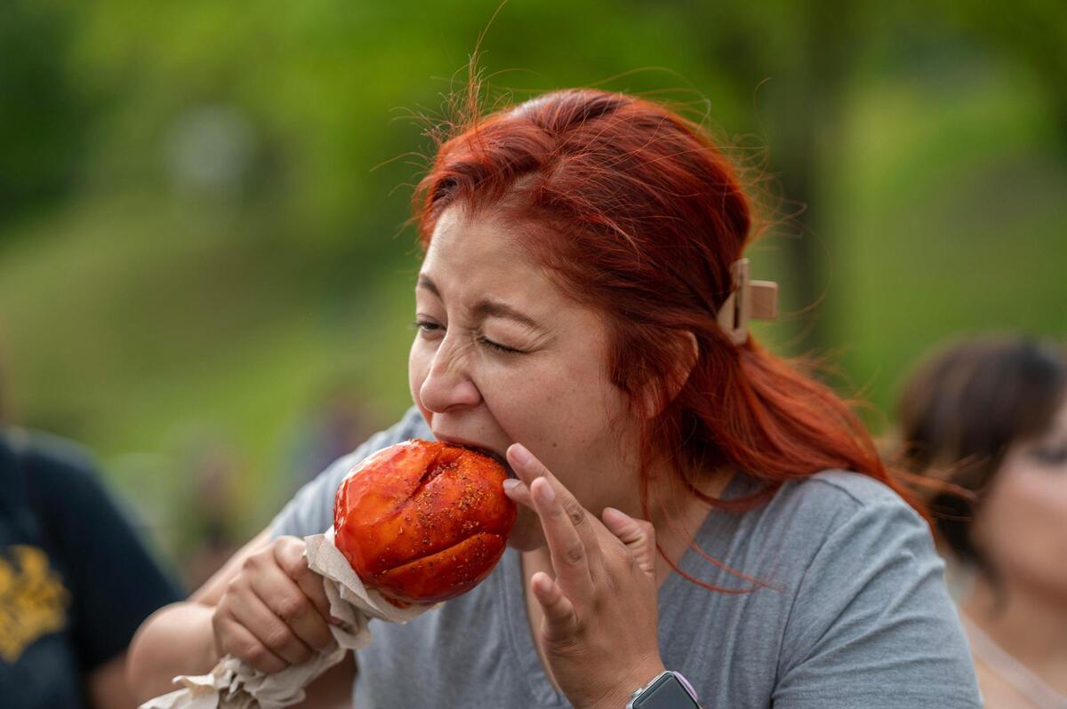 Marina Calvillo takes a bite out of a chili covered mango during the Cinco de Mayo celebration at Guadalupe Centers on Friday, May 5, 2023, in Kansas City.