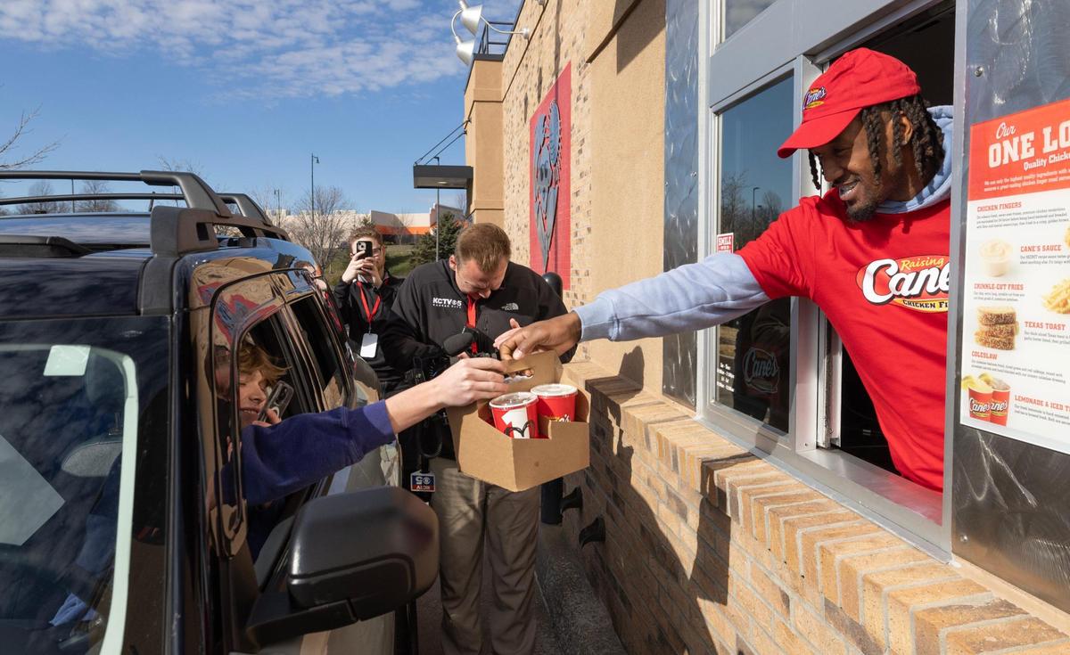 Kansas City Chiefs cornerback L’Jarius Sneed hands an order to fans while working at a Raising Cane’s restaurant in Blue Springs on Tuesday. Hardman was joined by teammate Mecole Hardman Jr. at the event.
