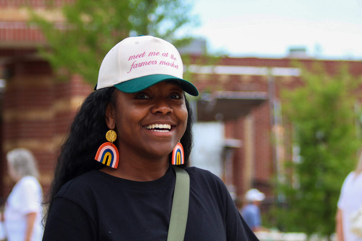 Chelsey M., 34, of Lee’s Summit, poses for a photo with her hat that reads, “Meet me at the farmer’s market,” on June 6, 2026.