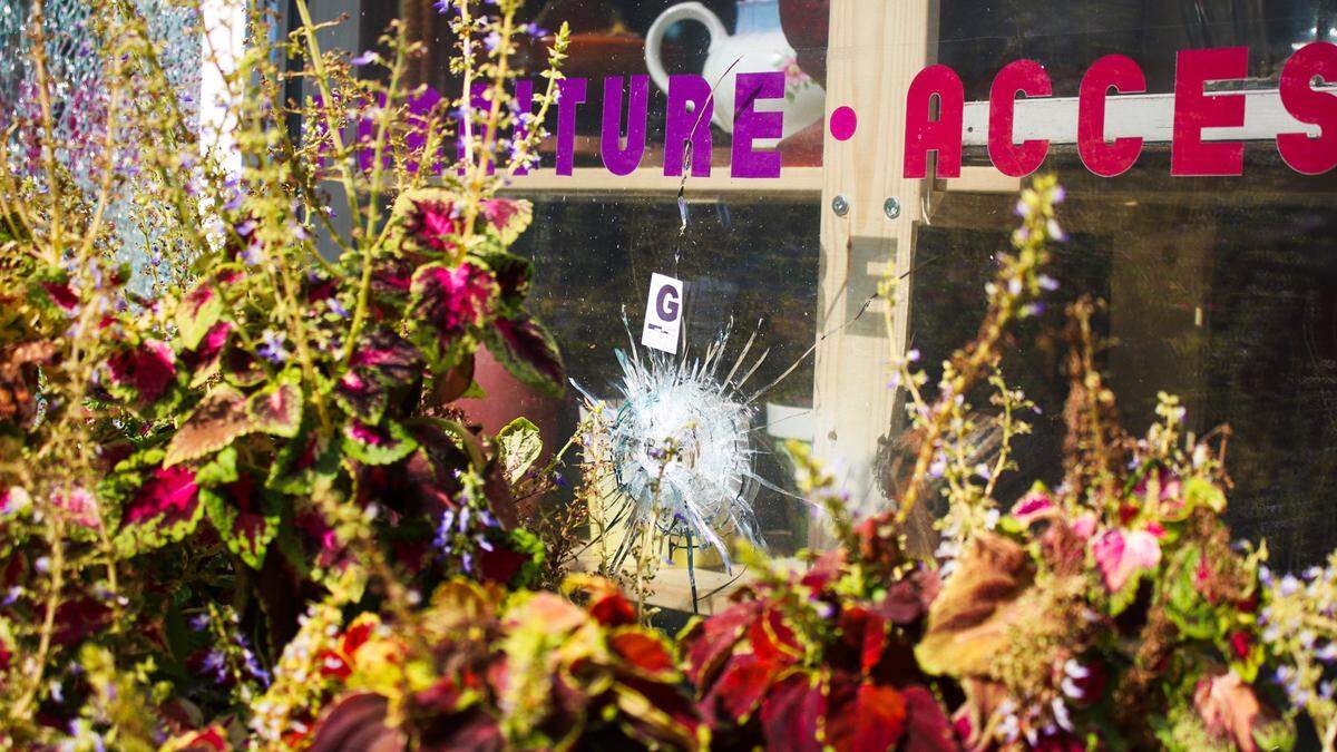 A bullet hole marked with police evidence tape is seen in the storefront of Pop! Vintage Furniture and Accessories’ Westport Road location. A shooting in the neighborhood injured 5 people Wednesday.
