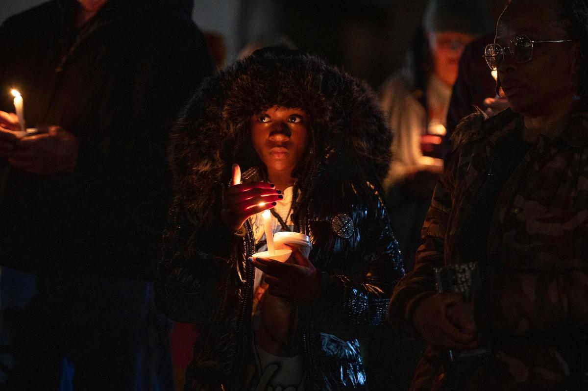 Myieema Gentry, 10, shields a candle with her hand as rain falls during a vigil as part of the Longest Night service at The Gathering Church on Thursday, Dec. 21, 2023, in Independence, Missouri. Community members gathered to honor the lives of homicide victims in Kansas City for 2023, uniting to read the names of these individuals, reflect on their legacies and offer support to those grieving the loss of their loved ones.