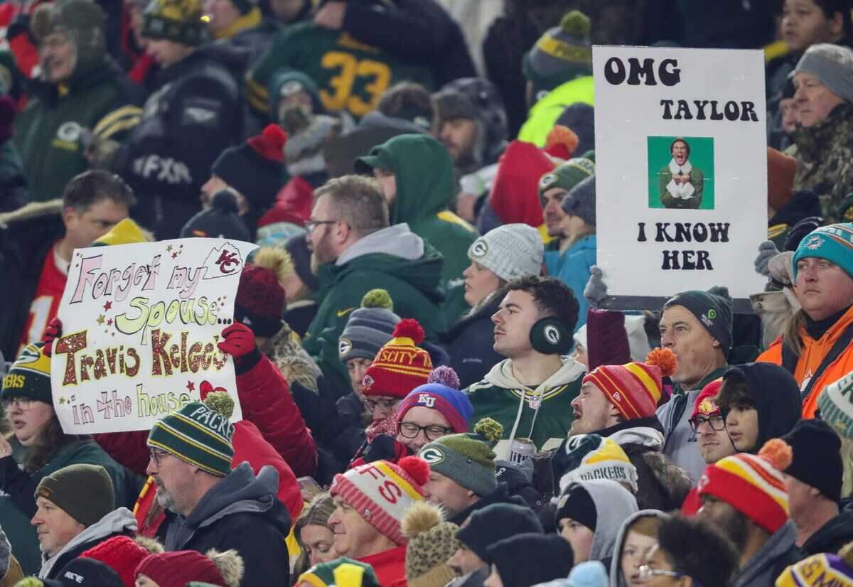 Fans hold up signs referencing pop star Taylor Swift and Kansas City Chiefs tight end Travis Kelce during a game between the Green Bay Packers and the Chiefs on Sunday, December 3, 2023, at Lambeau Field in Green Bay, Wisconsin.