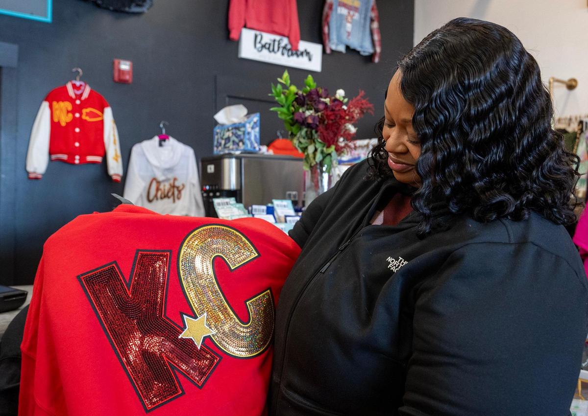 Markita Brown, a registered nurse from Lee’s Summit, proudly displays her custom sweatshirt, noting, “It’s $40, and it’s unique.” She chose a vibrant red sweatshirt adorned with an oversized KC appliqué crafted from red and gold sequins, accented by a gold sequined star. Brown said she was captivated by the design’s sparkle. It was one of two sweatshirts she purchased at Maxi Laine’s Boutique.