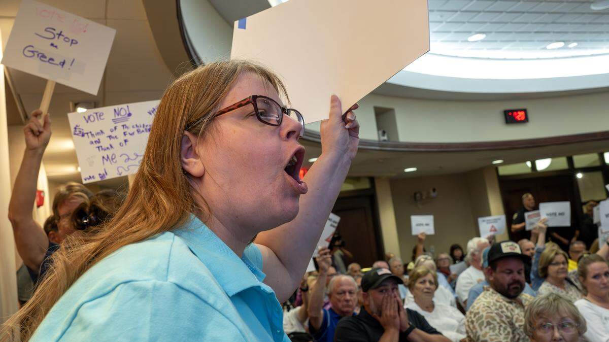 Suzanne Dougan yells while holding a sign during the Olathe City Council meeting on Tuesday, Sept. 16, 2025, at Olathe City Hall. The facility is planned near 175th Street and Lone Elm Road, where nearby residents have raised concerns about traffic, environmental and safety impacts.