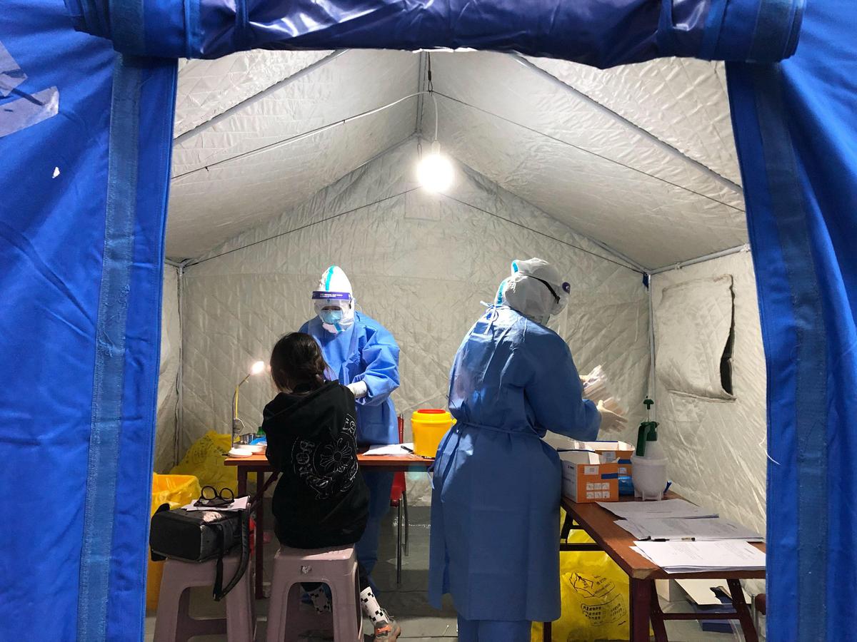 Inside a tent in an airport warehouse in Hohhot, two nurses did a throat swab and a blood test on an international traveler, checking for COVID-19.