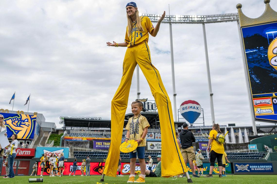 Savannah Bananas utility player Dakota Albritton (14) poses for a photo with five-year-old Gracyn Marx of South Dakota during VIB fan access before a Banana Ball game against the Firefighters at Kauffman Stadium on Friday, May 23, 2025, in Kansas City.
