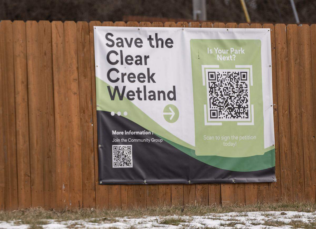 A community group banner hangs on a fence near the Clear Creek Trail on Monday, Feb. 2, 2026, as the city considers a 50-home Habitat for Humanity development in Lenexa. Located off Clare Road near 86th Terrace, the proposed site includes a walking trail that leads to a small lake and a surrounding wetlands area.