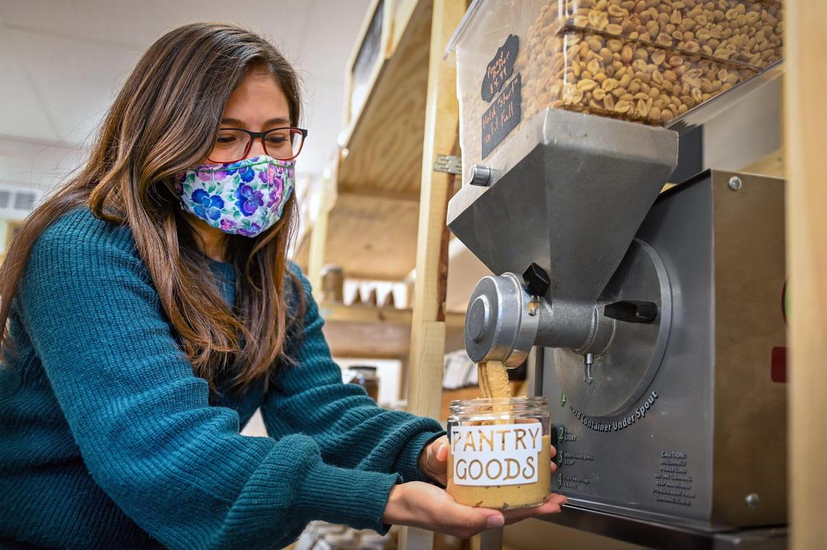 Employee Claudia Alcantara let freshly made peanut butter pour into a reusable jar at Pantry Goods, 910 W. 39th St.