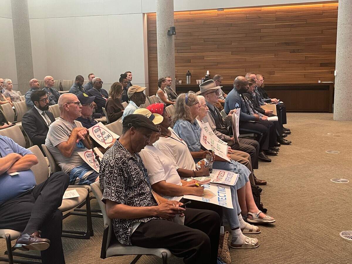 Members of Good Trouble KC held protest signs during the monthly meeting of the Kansas City Board of Police Commissioners on Tuesday, Aug. 22, 2023, where they requested the police board to hire a firm to study racial bias in the police department.