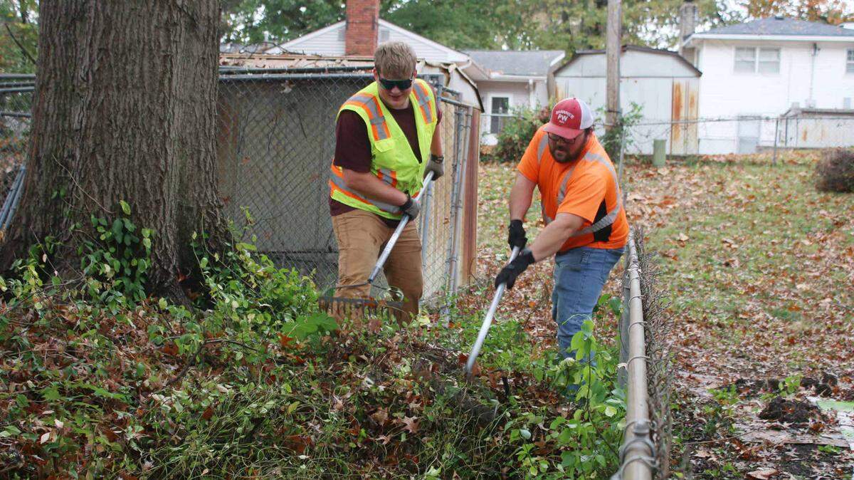 Jordon Williams and Josh Schulz clear out overgrown plants while volunteering with Neighbors Helping Neighbors.