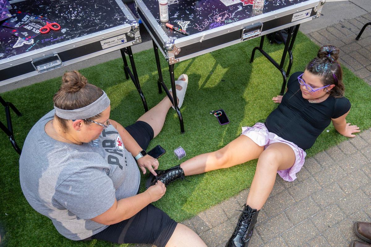 Merrily Vandiver, left, helps her daughter Avery Vandiver bedazzle her Doc Marten boots near the Customization Station by Doc Martens before the Olivia Rodrigo Guts World Tour concert at T-Mobile Center on Friday, July 26, 2024, in Kansas City.