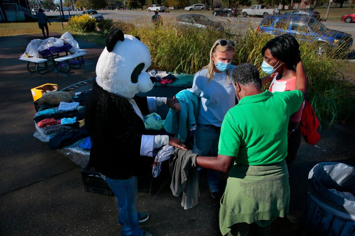 Gelender Shannon, left, Venus Nisbet, and Donna Washington, pray with a woman at right whose son was recovering from gunshot wounds to his stomach, during a food and clothing giveaway in a private park at the corner of North Grand Boulevard and Barrett Street on Thursday, Oct. 22, 2020. Shannon, 65, wears a panda head along with a regular mask to keep safe when going out in crowded areas.