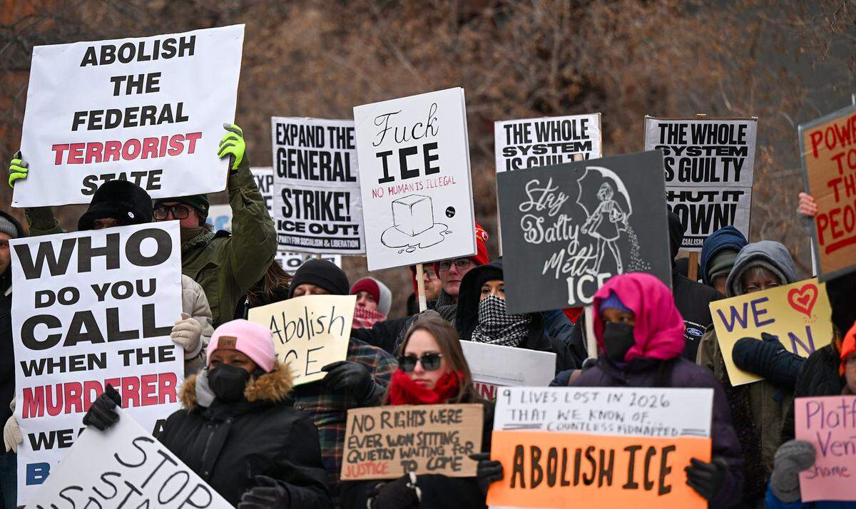 Protesters hold up several signs, joining nationwide demonstrations against ICE in downtown Kansas City in freezing temperatures on Friday, Jan. 30, 2026.