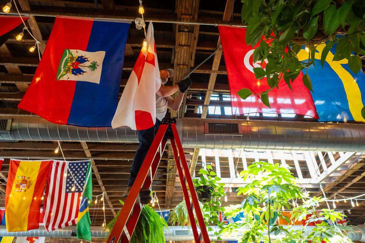 Owner Kyle Gray hangs a flag in the interior of Casual Animal Brewing Co. on Monday, May 4, 2026. The owners are hanging flags for the participating World Cup national teams in anticipation of the event.